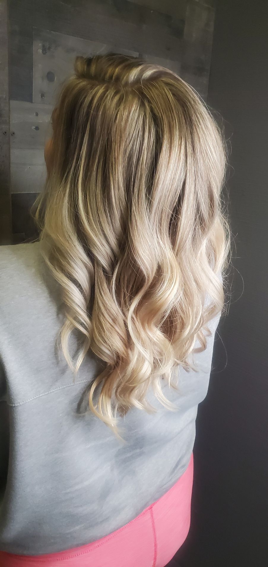 A woman with blonde hair is wearing a gray shirt and pink pants.