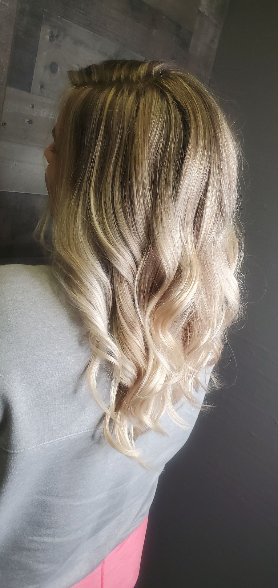 A woman with blonde hair is wearing a gray sweater and pink pants.