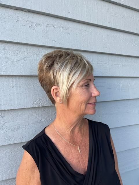 A woman with short blonde hair is standing in front of a building