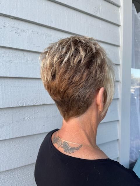 A woman with short hair has a tattoo on her back