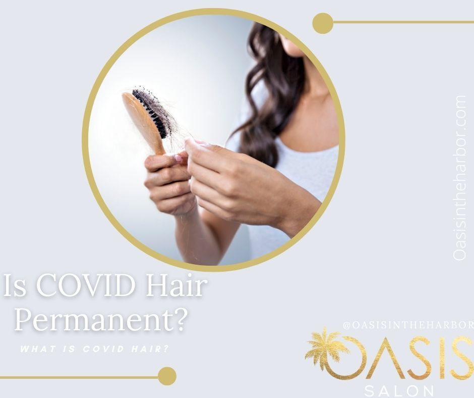 A woman is holding a brush and looking at her hair.