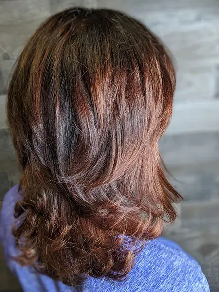 A woman with long brown hair is wearing a blue shirt.