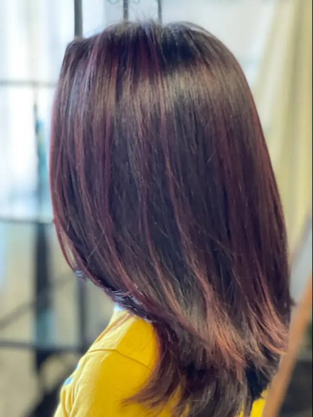 A woman with long dark hair is wearing a yellow shirt.