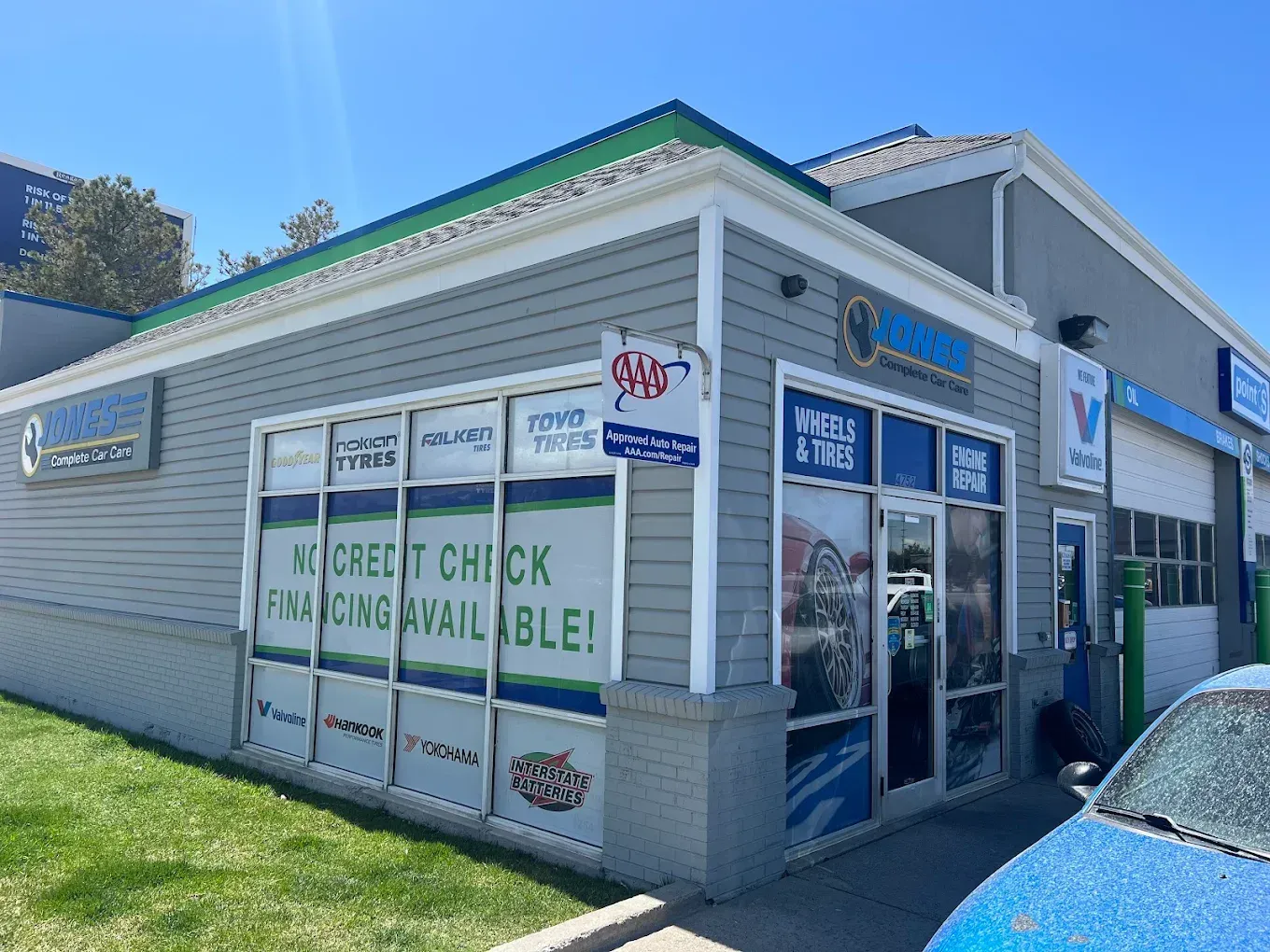 Corner storefront with blue trim and signs, including a walk-in clinic and credit check cashing service. | Jones Complete Car Care