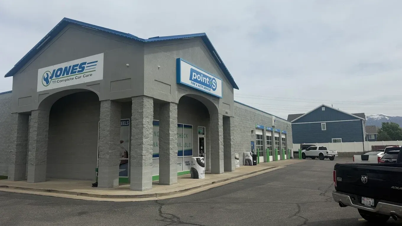 Commercial building with blue-and-white signs and covered entrance in a parking lot | Jones Complete Car Care
