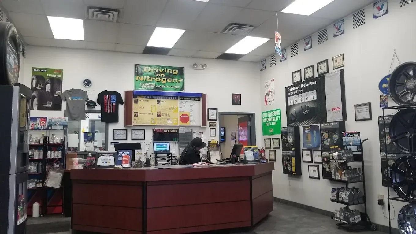 Auto shop reception area with a red front desk, wall signs, and framed certificates. | Jones Complete Car Care