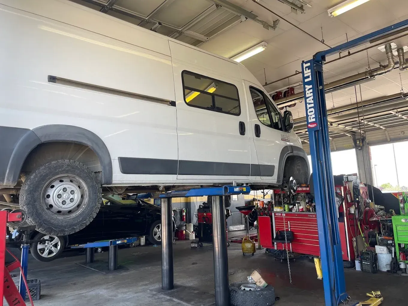 White van lifted on a shop lift inside an auto repair garage. | Jones Complete Car Care