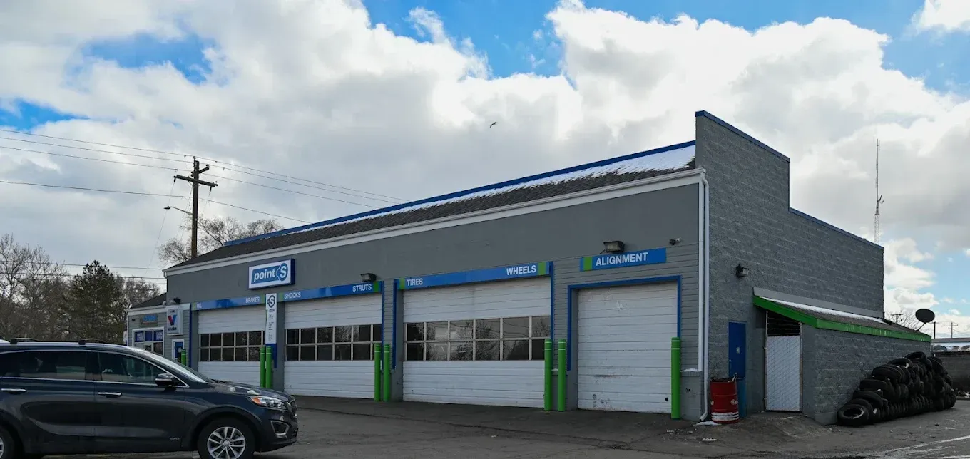 Gray auto shop building with blue trim and parked cars on a cloudy street | Jones Complete Car Care