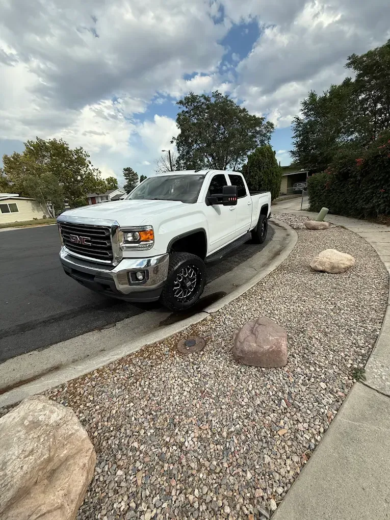 White pickup truck parked on a curved gravel driveway beside boulders under a cloudy sky | Jones Complete Car Care