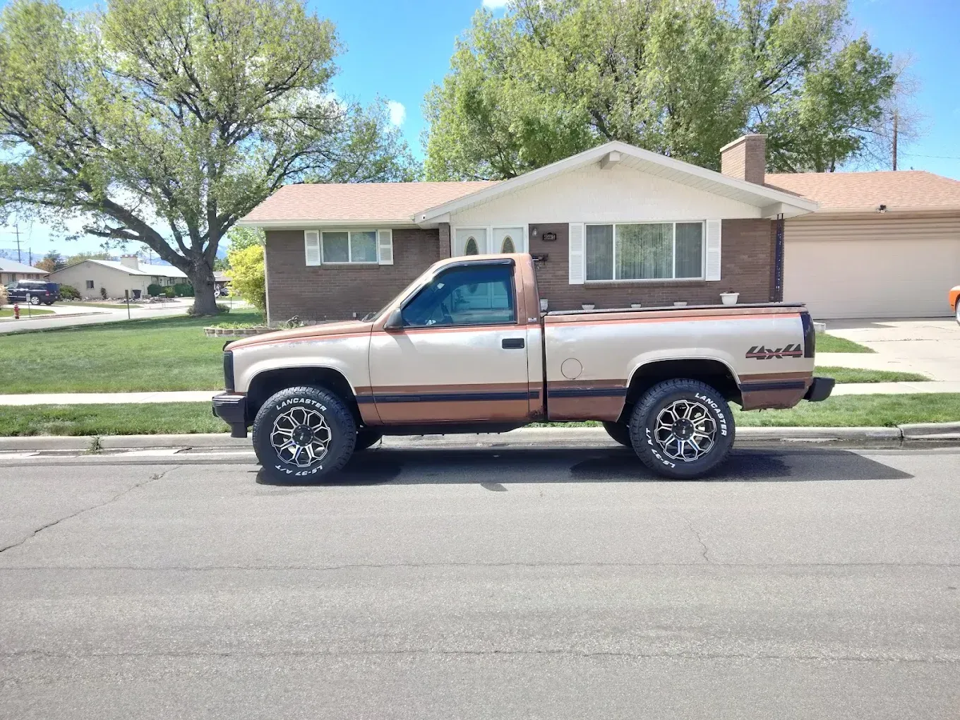 Beige pickup truck parked on a residential street in front of a brick house. | Jones Complete Car Care