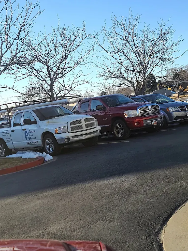 Parked cars in a lot, including a white pickup and red SUV, under bare trees on a clear day | Jones Complete Car Care