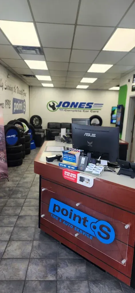 Cell phone store counter with Point S branding, TV monitor, tires, and a Jones sign in the background | Jones Complete Car Care