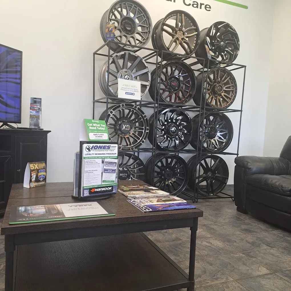 Auto wheel display in a shop showroom with stacked rims, a coffee table, and a black couch. | Jones Complete Car Care