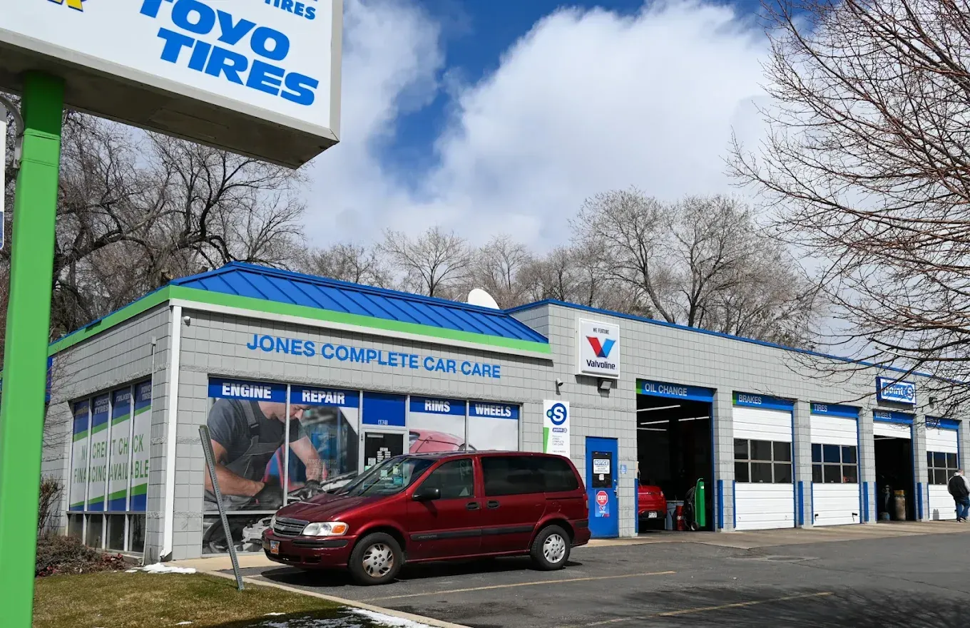 Auto service shop exterior with a red SUV parked in front and a Toyo Tires sign overhead | Jones Complete Car Care