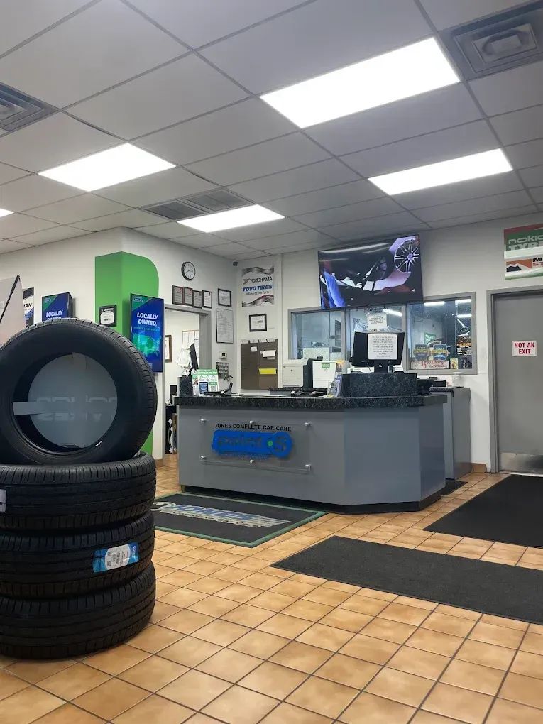 Auto repair shop interior with stacked tires, service counter, and hanging TVs | Jones Complete Car Care