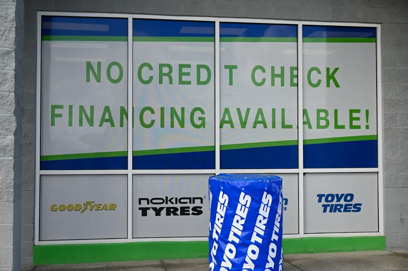 Storefront window with “No credit check financing available” sign and tire brand logos | Jones Complete Car Care