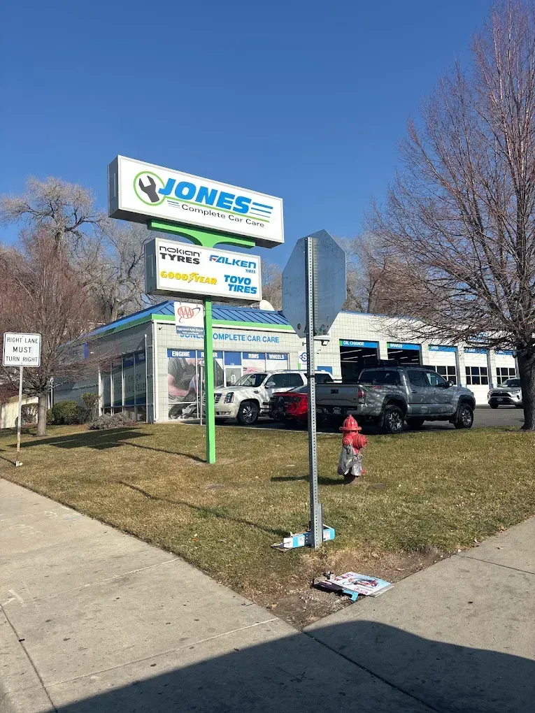 Car dealership lot with parked cars, a sign, and a small red fire hydrant on a sunny day | Jones Complete Car Care