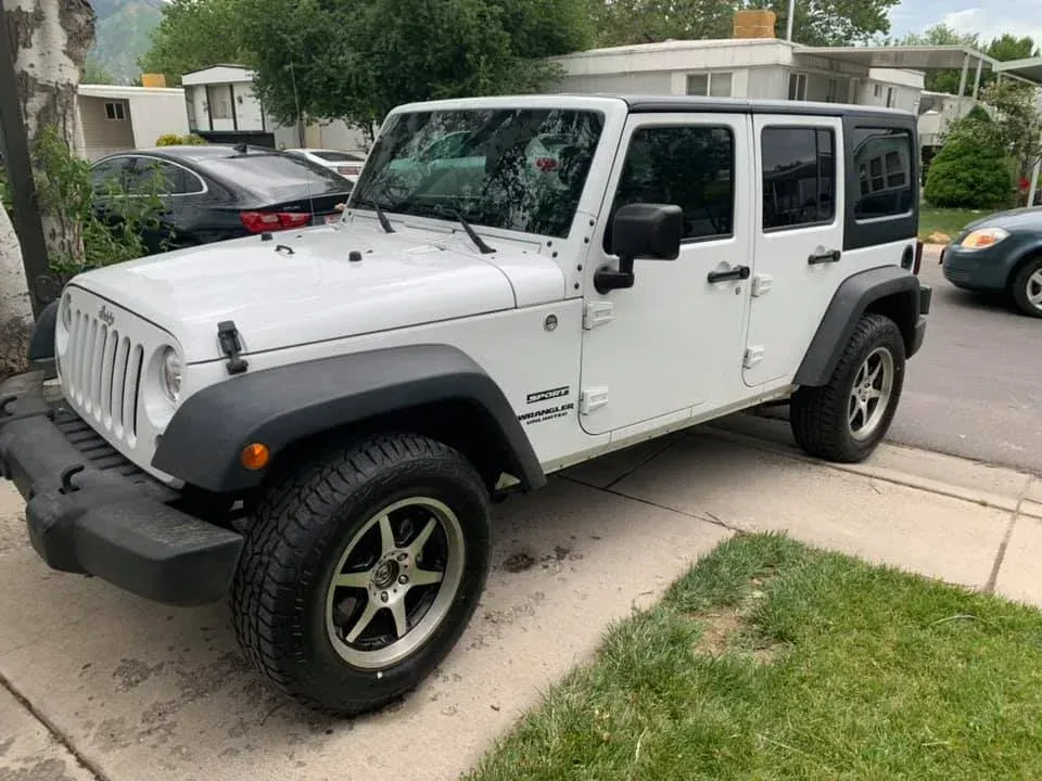 White Jeep Wrangler parked on a residential street beside a sidewalk and lawn | Jones Complete Car Care