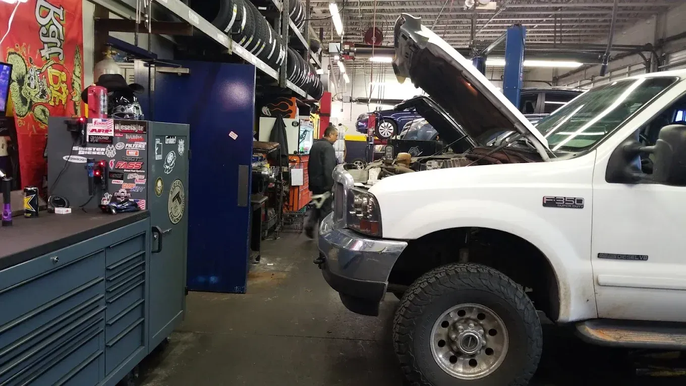 White pickup truck in an auto repair shop with hood open, surrounded by tools and equipment. | Jones Complete Car Care