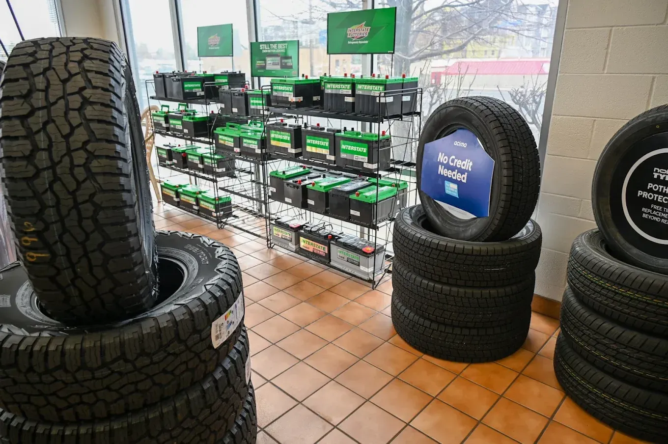 Tire shop display with stacked black tires and rows of green-and-black tire boxes by a window | Jones Complete Car Care