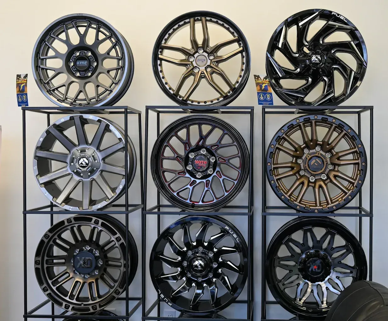 Three rows of decorative car rims/wheels displayed on metal racks in a showroom. | Jones Complete Car Care