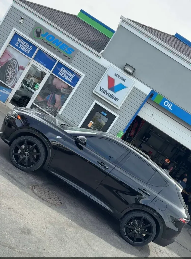 Black SUV parked outside an auto service shop with blue signage and garage bays | Jones Complete Car Care