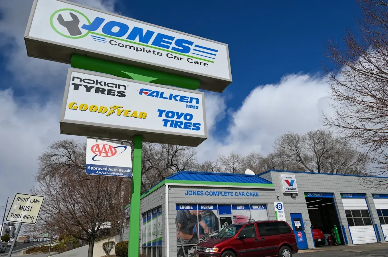 Jones Tire Center sign above a storefront with a red SUV parked outside under a blue sky | Jones Complete Car Care