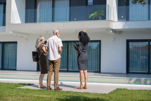 A group of people are standing in front of a large house.