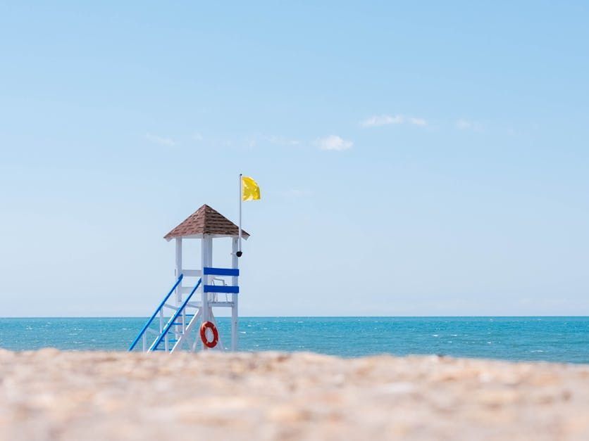 A lifeguard tower on a beach with a yellow flag.