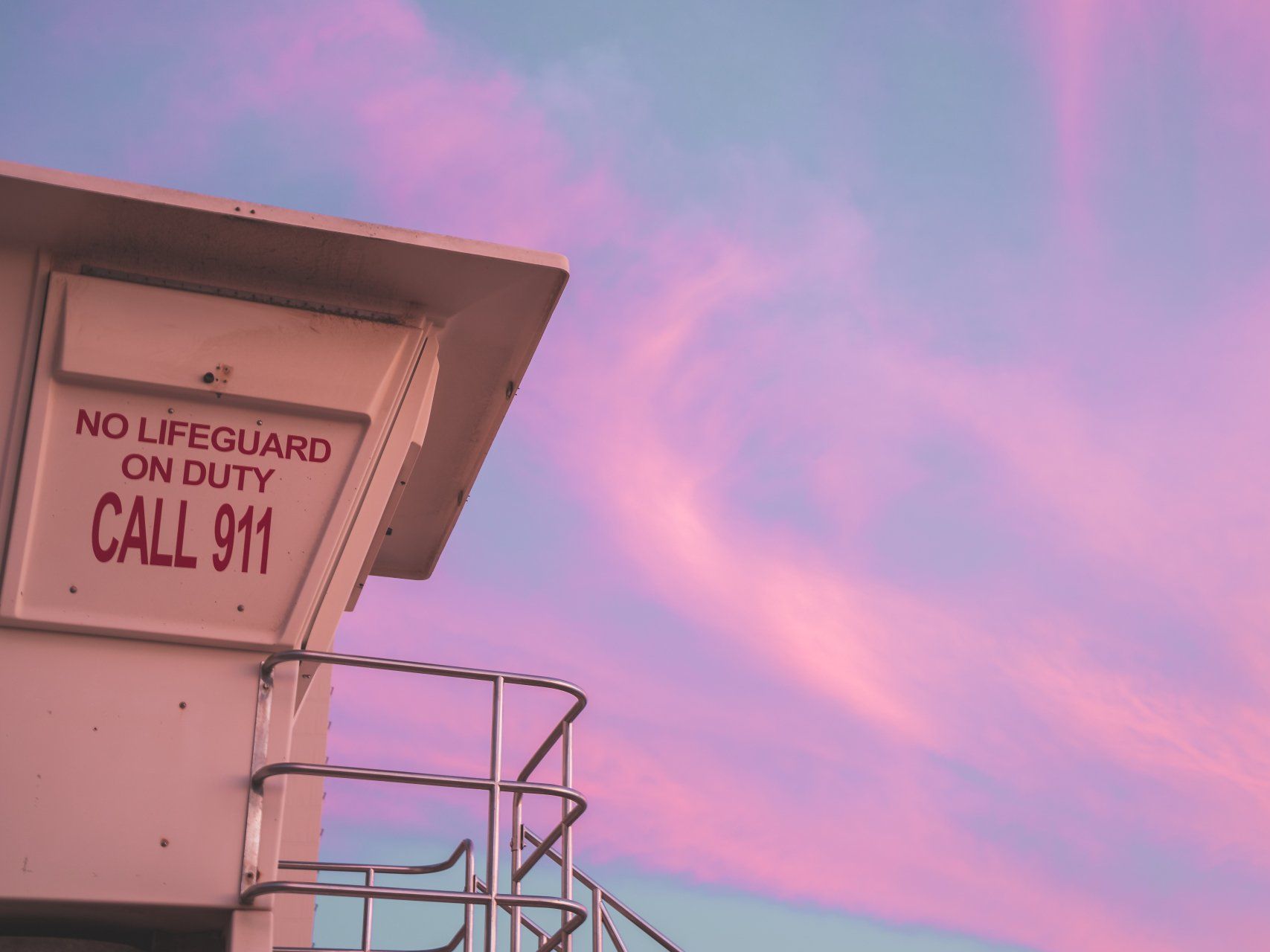 A lifeguard tower with a pink sky in the background.