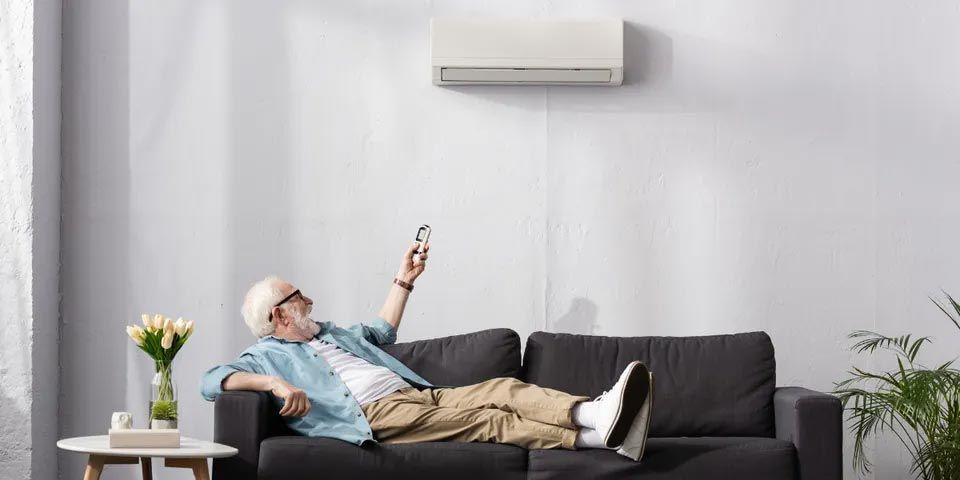 Senior Man Turning On the Air Conditioner — Vashon, WA — Vashon Heating & Cooling