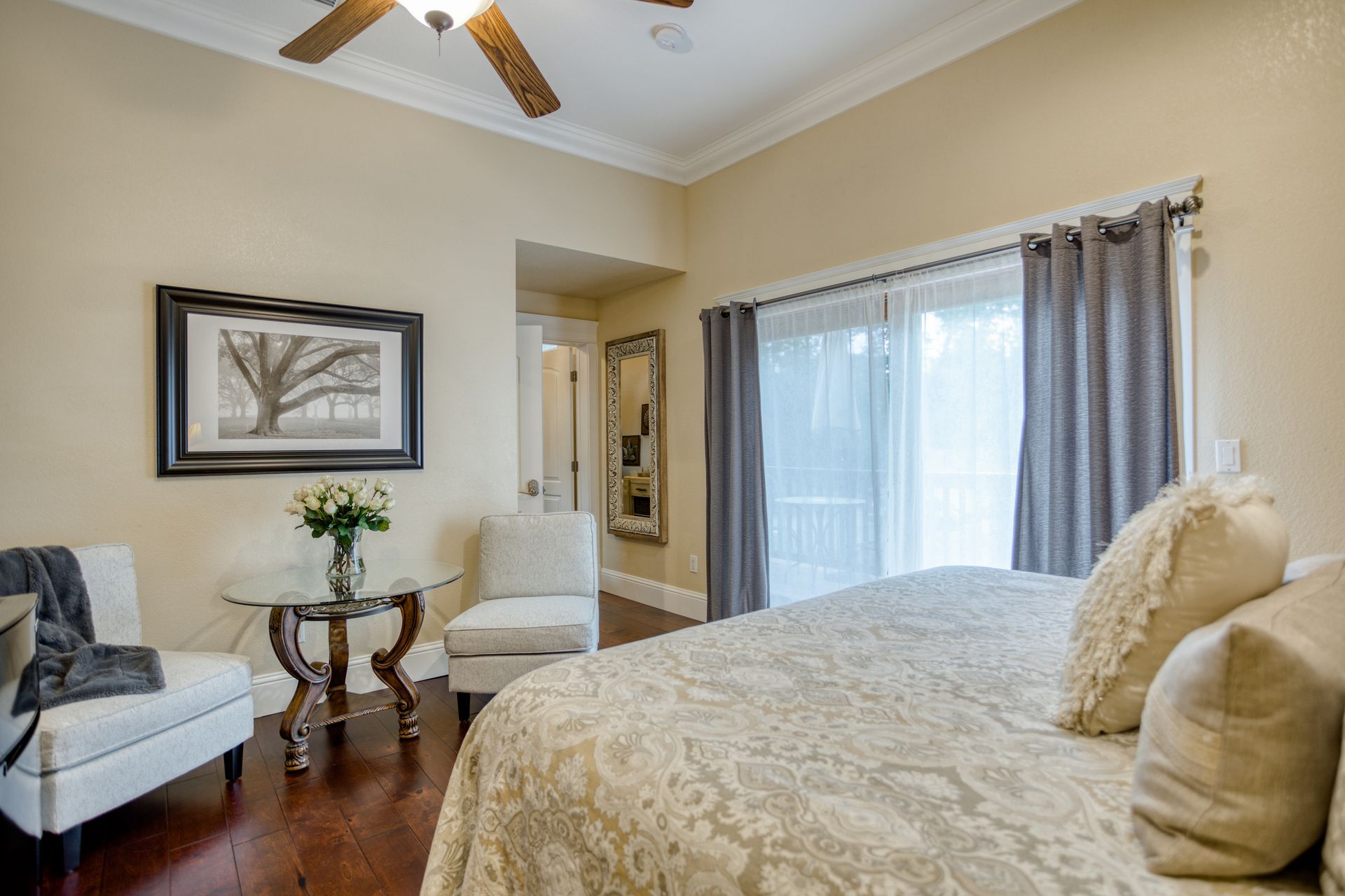 A bedroom with a bed , chair , table and ceiling fan.