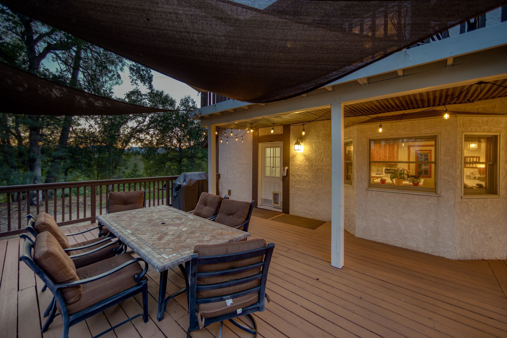 A large deck with a table and chairs under a canopy.