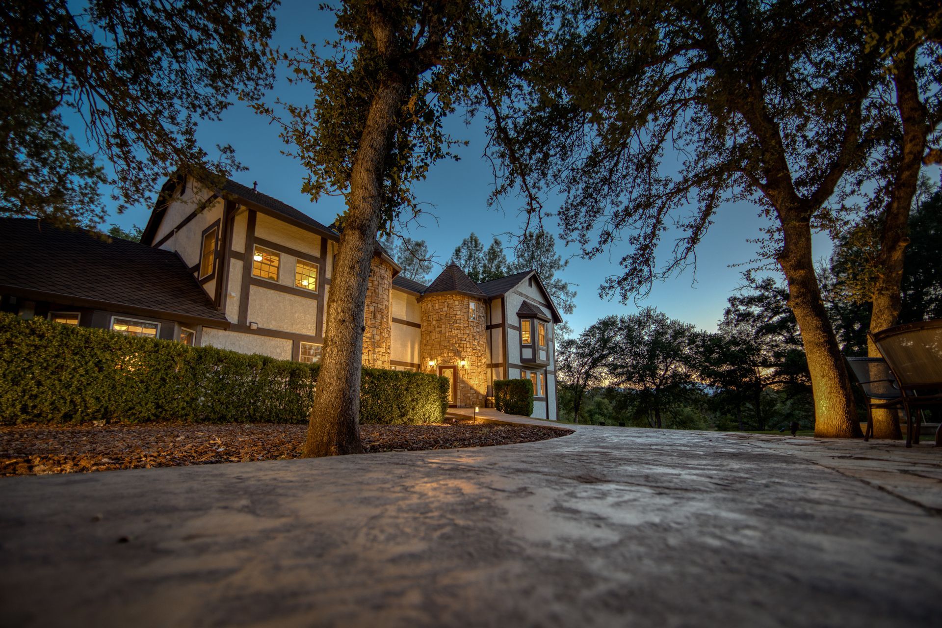 A large house is lit up at night with trees in front of it.