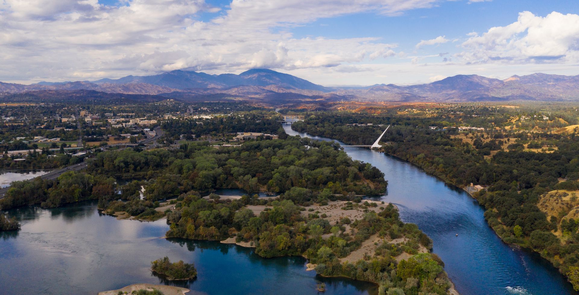 An aerial view of a river surrounded by trees and mountains.