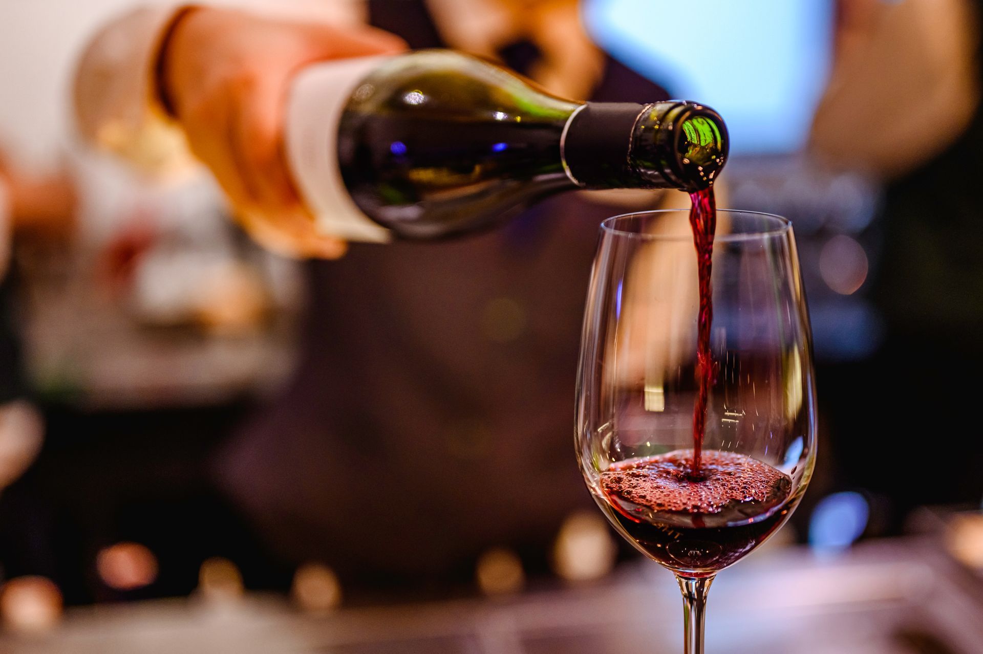 A person is pouring red wine into a glass.