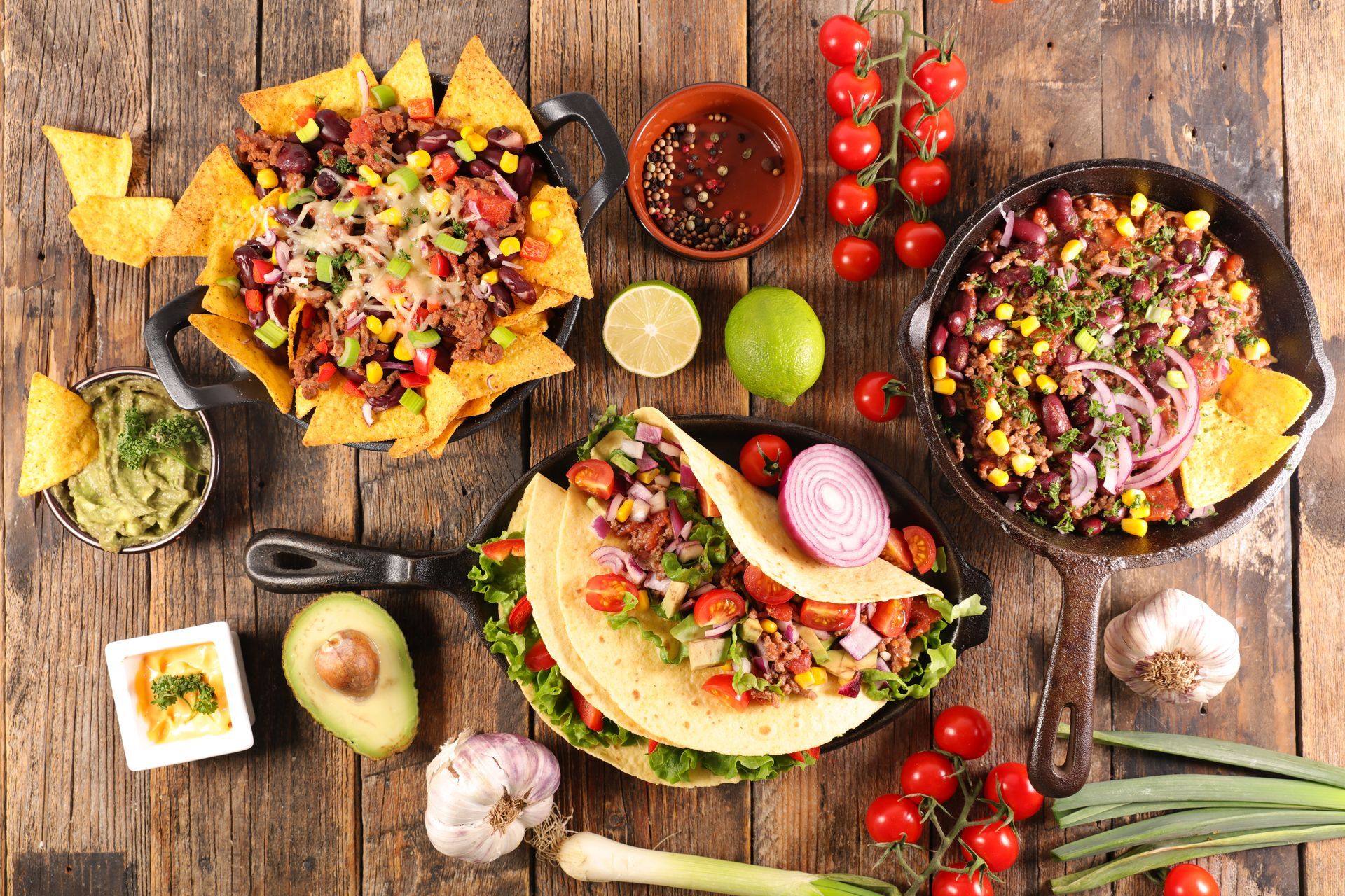 A wooden table topped with a variety of mexican food.
