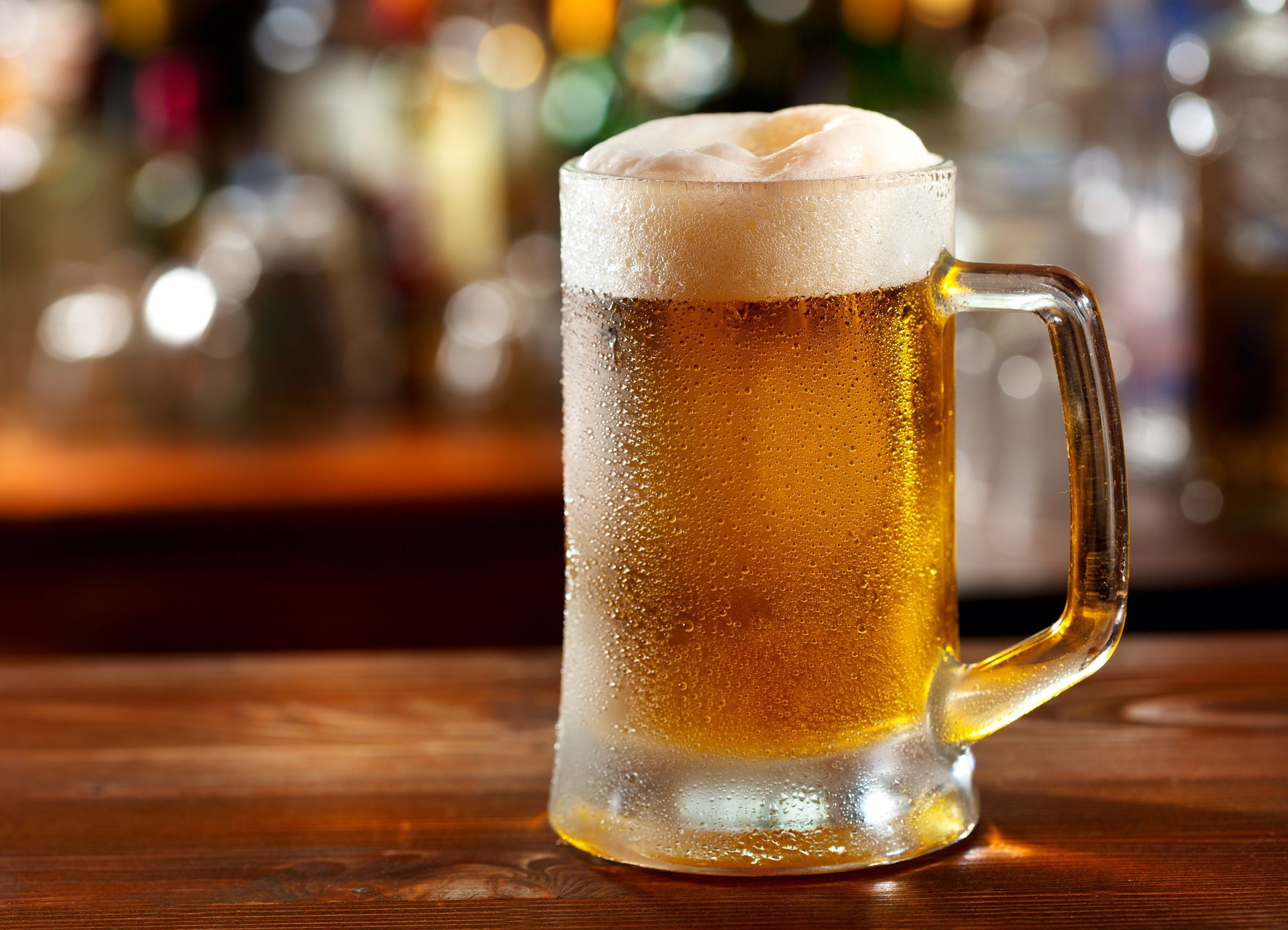 A glass of beer is sitting on a wooden table.
