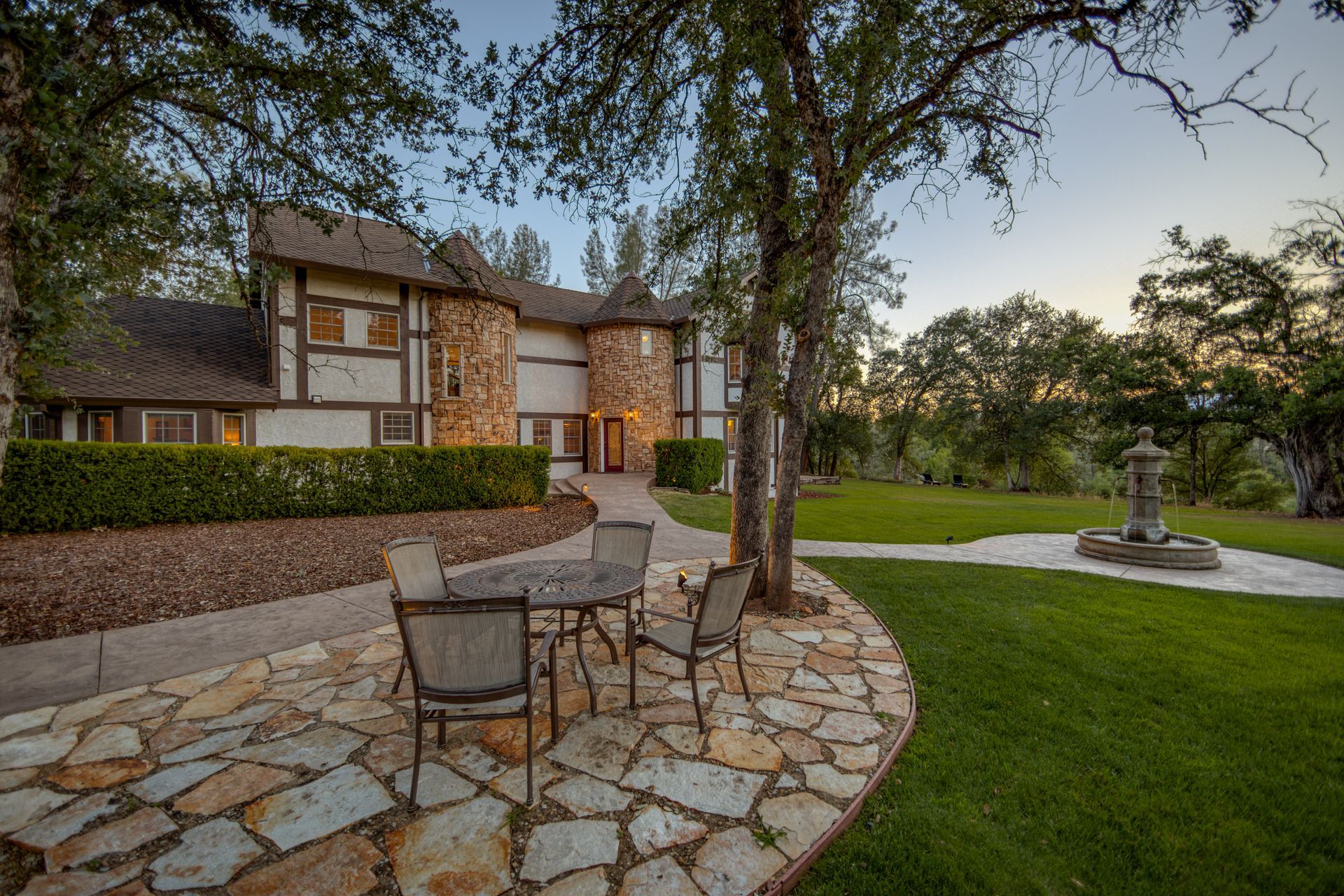 A stone patio with a table and chairs in front of a large house