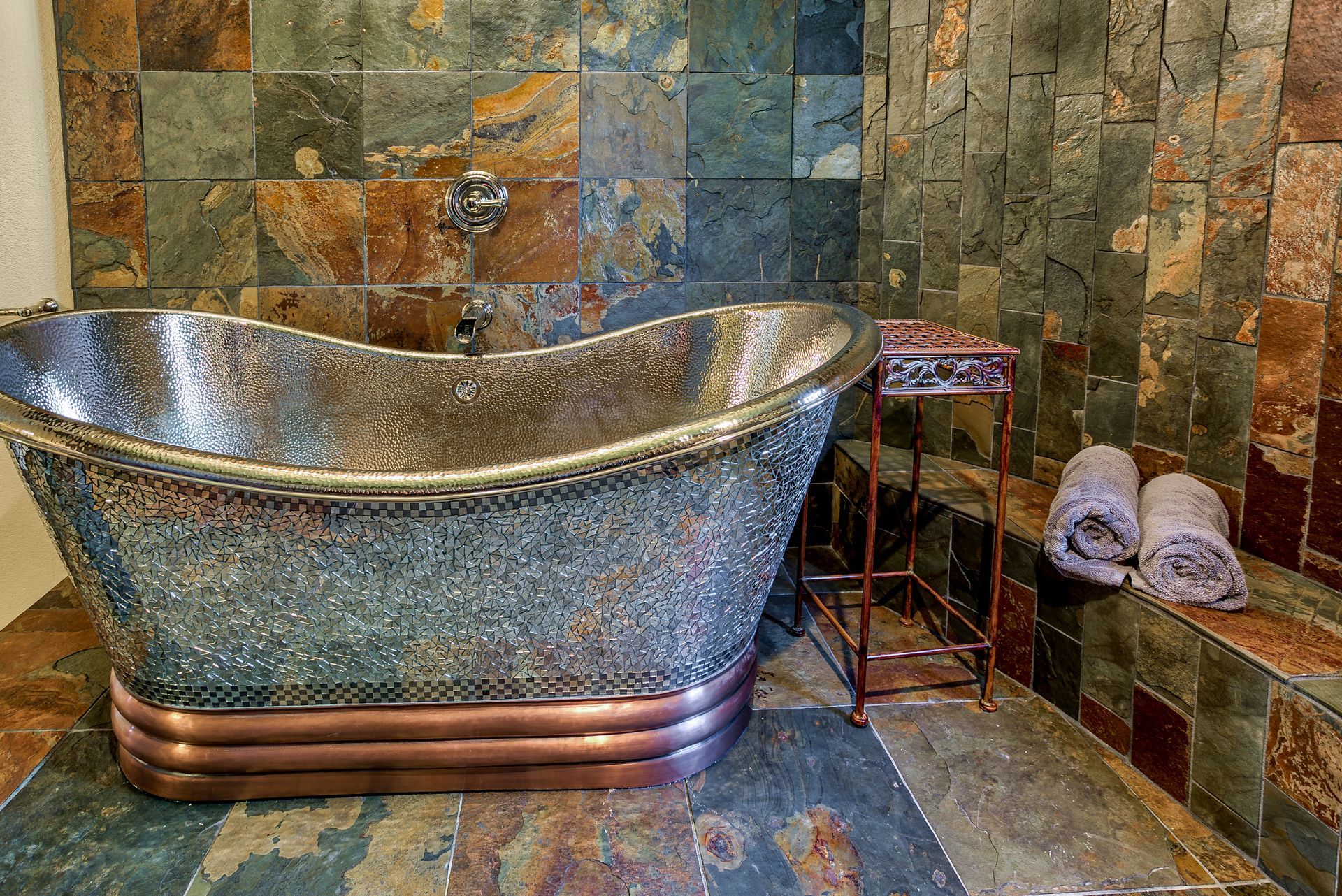 A bathtub is sitting in a bathroom next to a stone wall.
