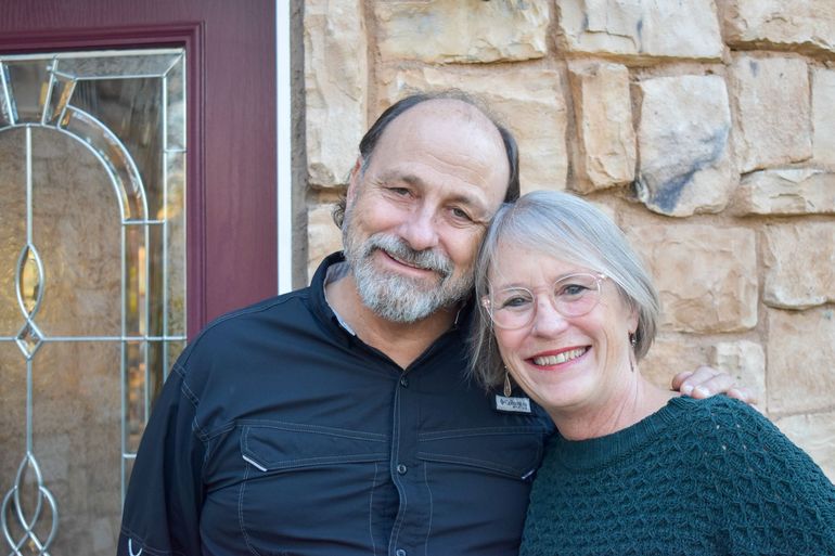 A man and a woman are posing for a picture and smiling for the camera.