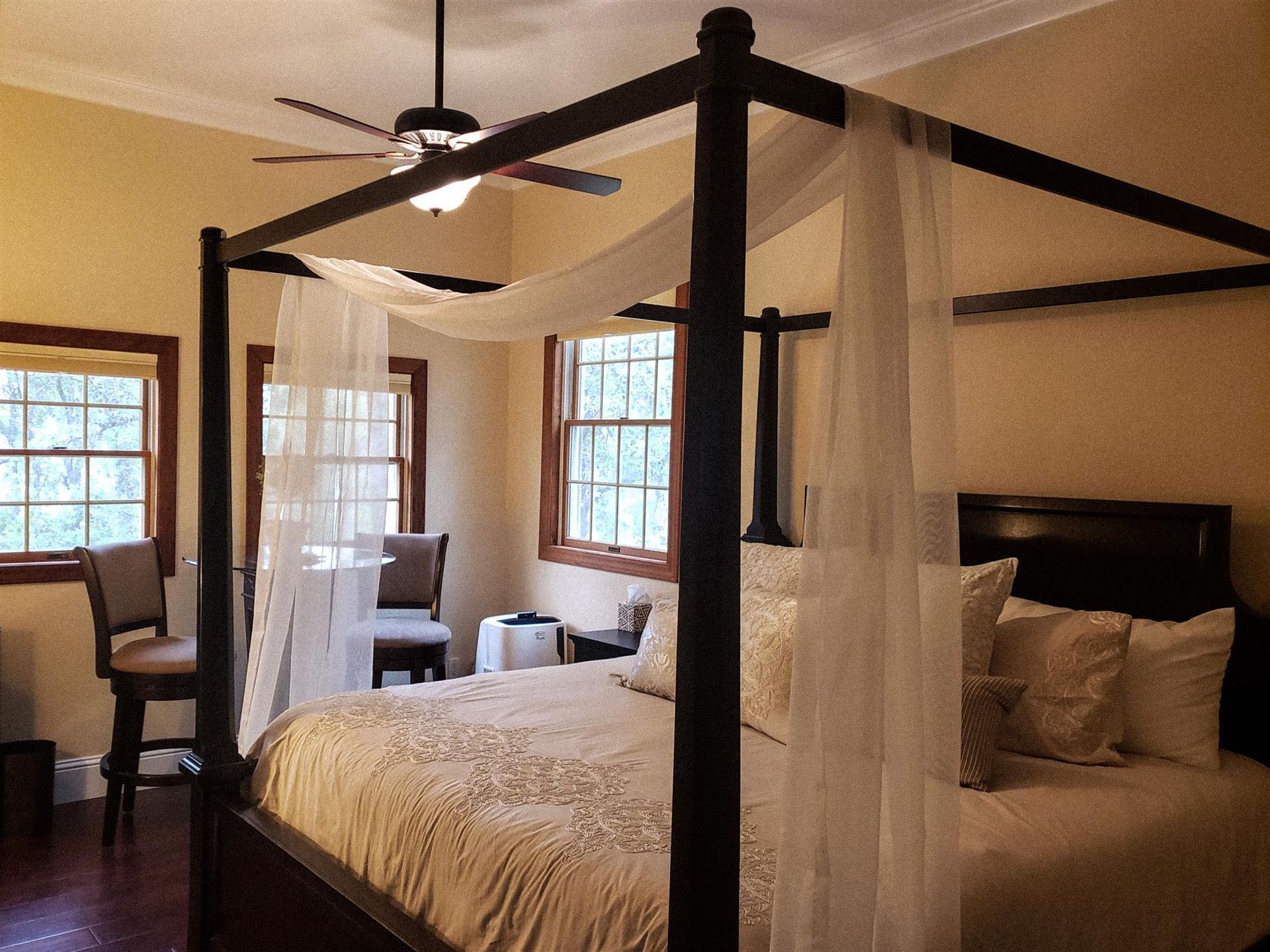 A bedroom with a canopy bed and a ceiling fan