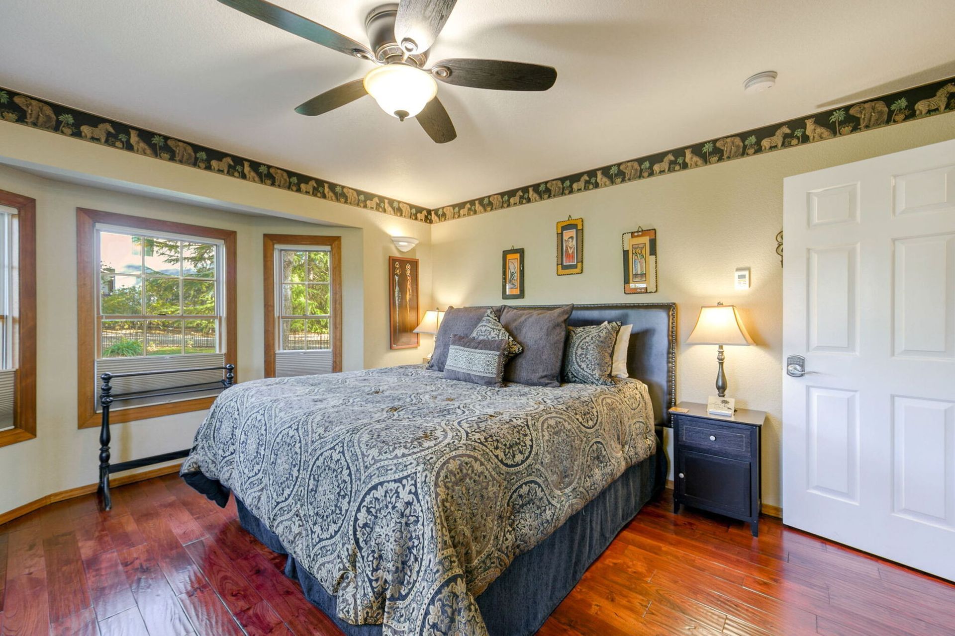 A bedroom with a bed , chair , table and ceiling fan.