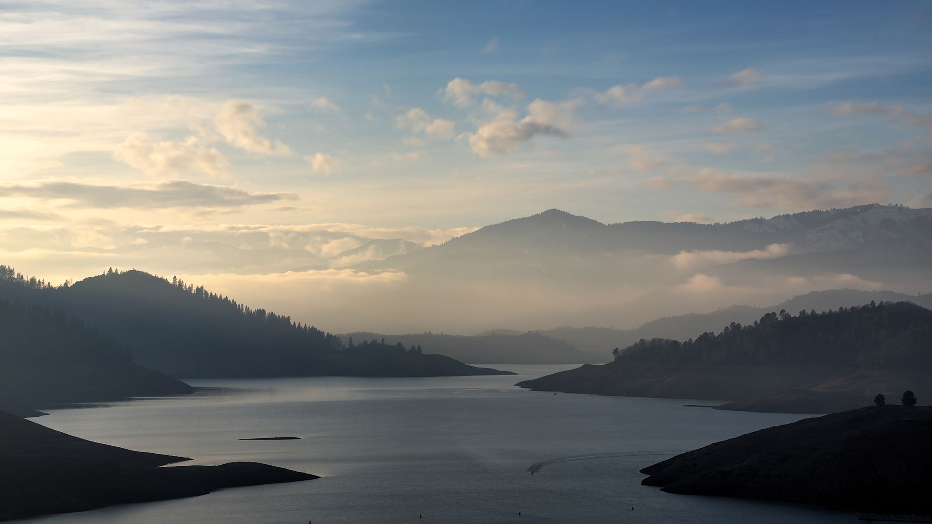 A lake with mountains in the background and a cloudy sky