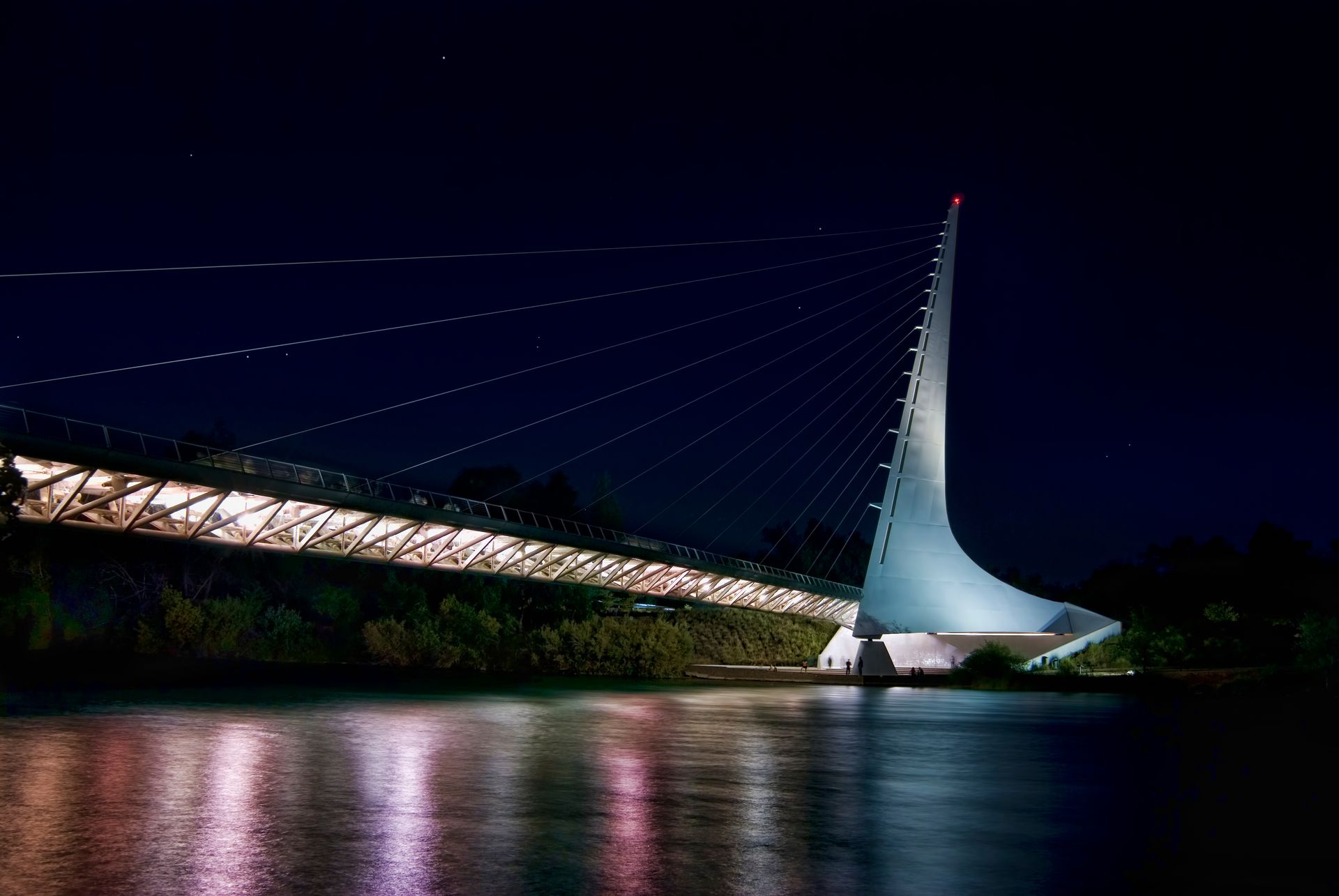 A bridge over a body of water at night.
