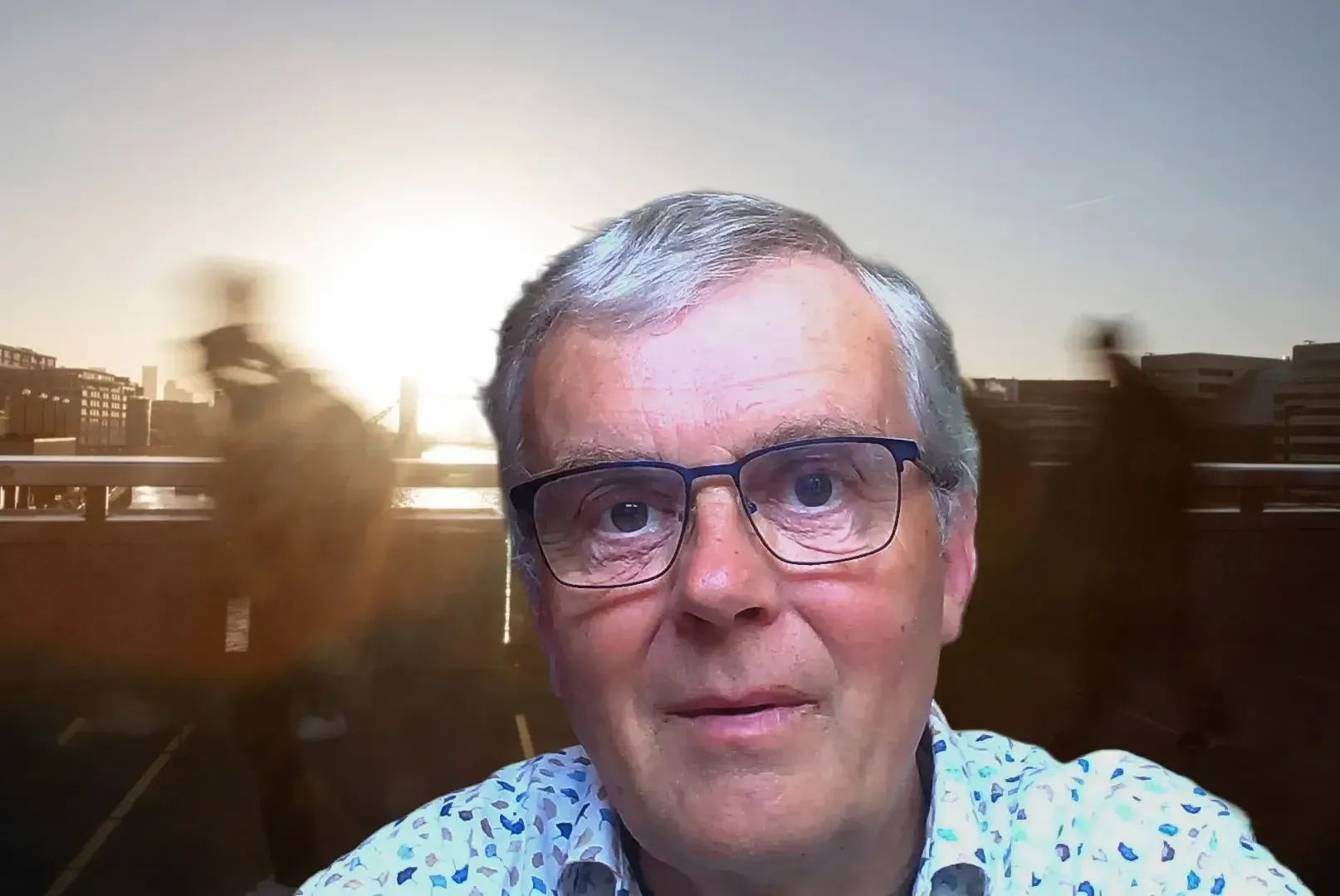 Man met een bril voor een wazig buitentafereel bij zonsondergang.