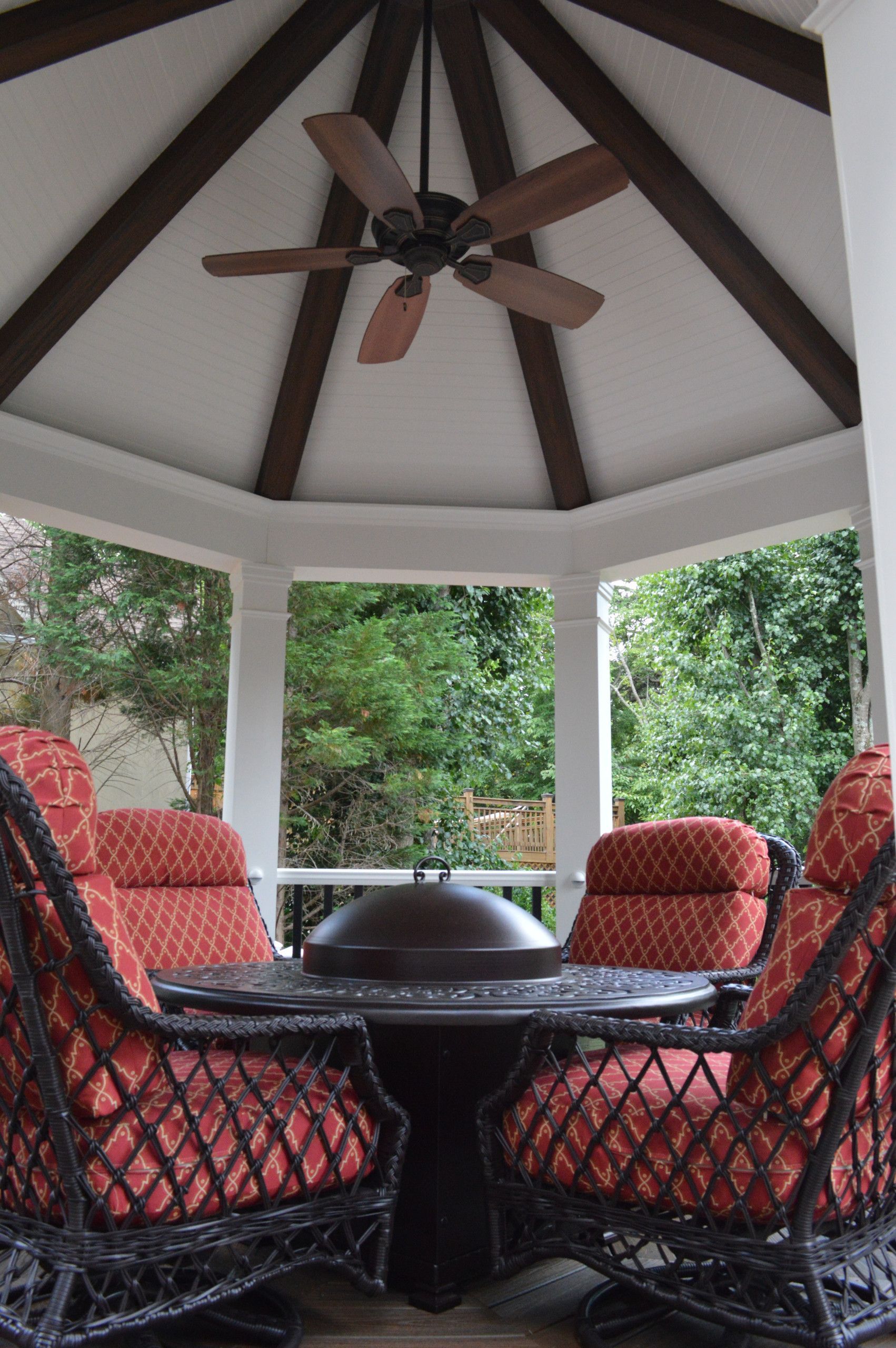 A gazebo with a table and chairs and a ceiling fan