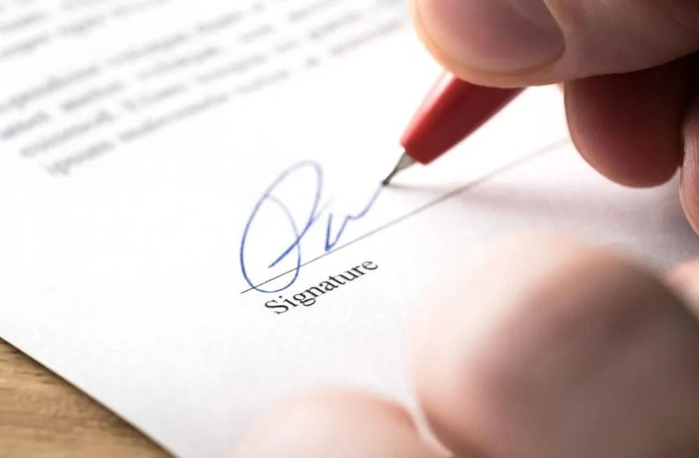 Hand Signing Document with Red Pen on 
