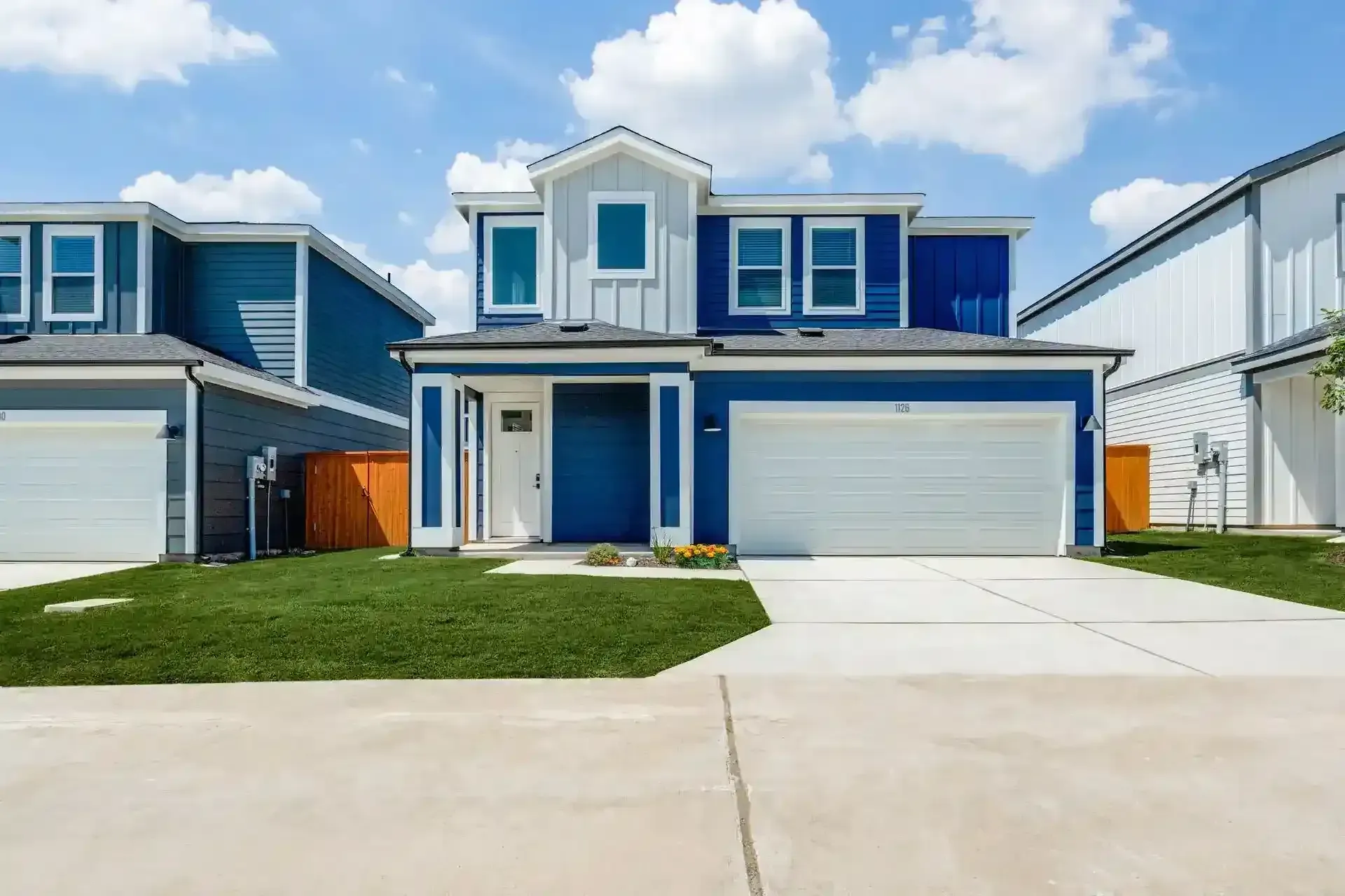 Exterior view of a blue and gray house with a driveway and garage