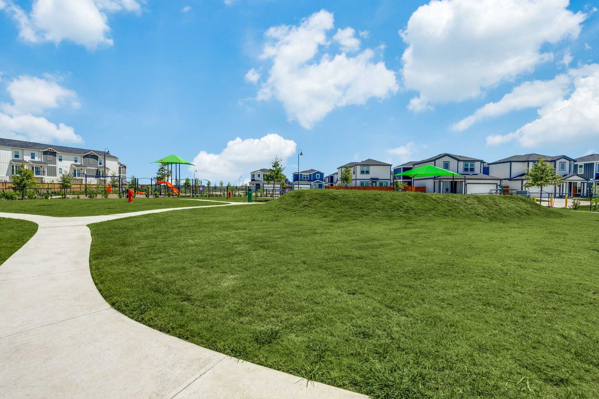 Spacious park area with playground and homes in the background